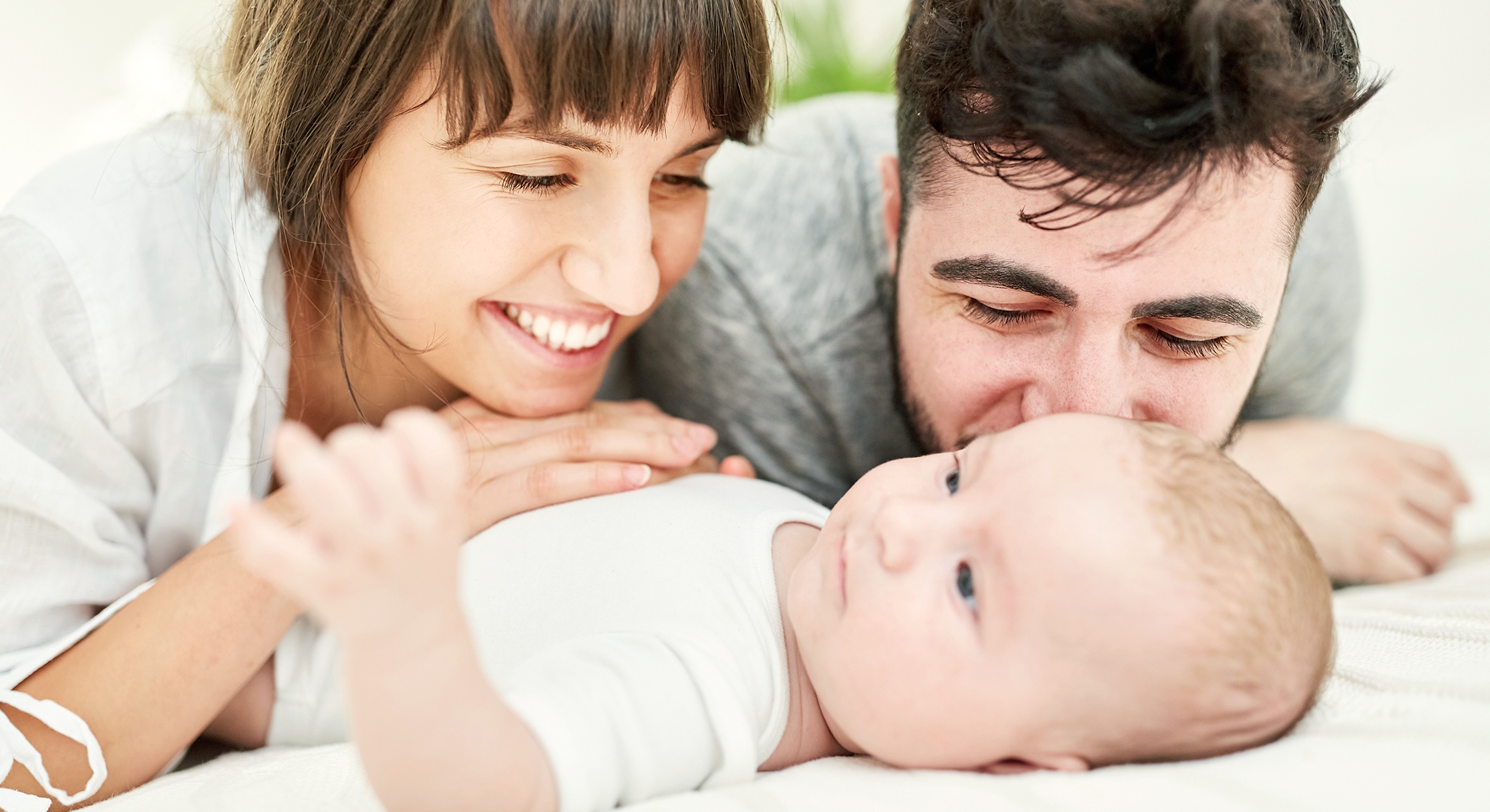 Mann und Frau schmusen mit Säugling das auf einer Decke liegt