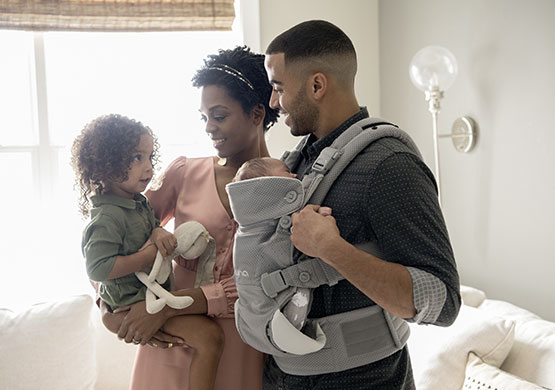 Mann mit einer Bauchtragen der Firma "nuna"