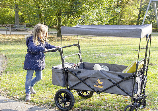Kinder unterwegs mit einem Bollerwagen der Firma Pinolino